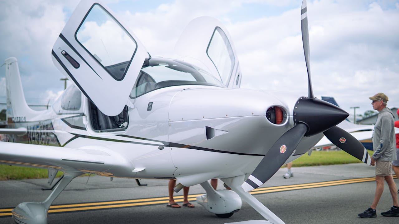 Sleek white aircraft with propeller and open doors on a runway, showcasing modern aviation design.
