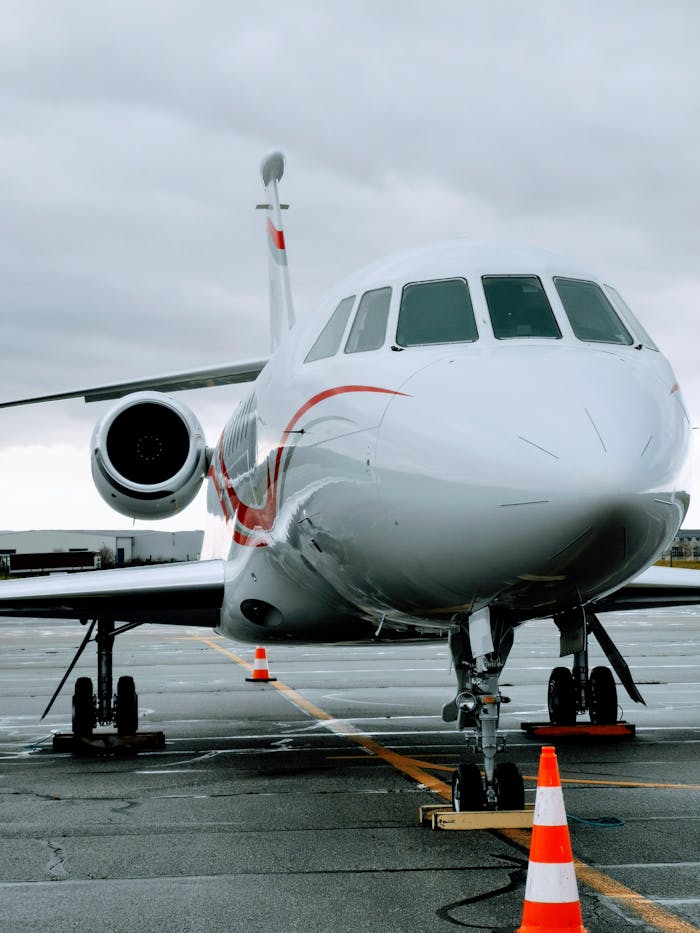 services-01 A sleek modern jet aircraft parked on the runway at Grenoble airport, France under cloudy skies.