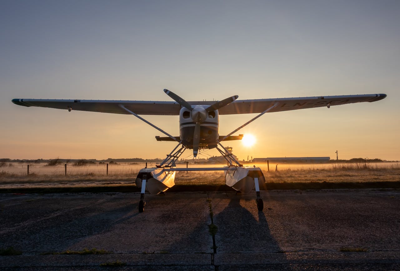 A seaplane rests on a runway at sunrise with misty surroundings, creating a serene aviation scene.