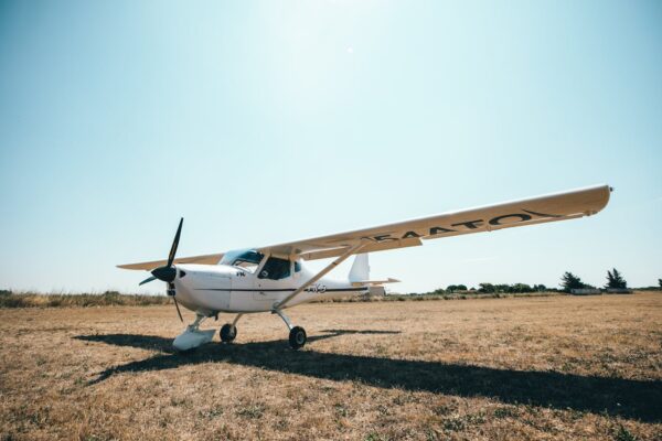 A light aircraft parked on a grassy airfield, captured on a sunny day.
